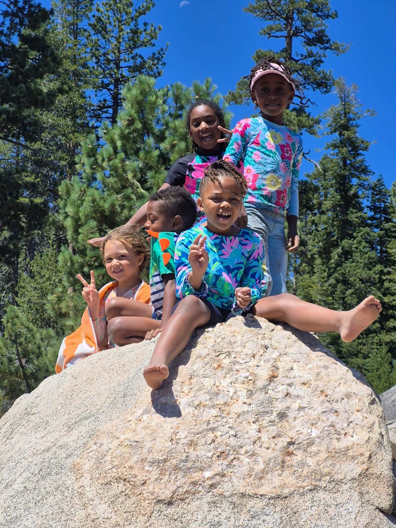 Five kids in rash guards piled on a granite boulder, grinning and flashing peace signs at Spicer Reservoir