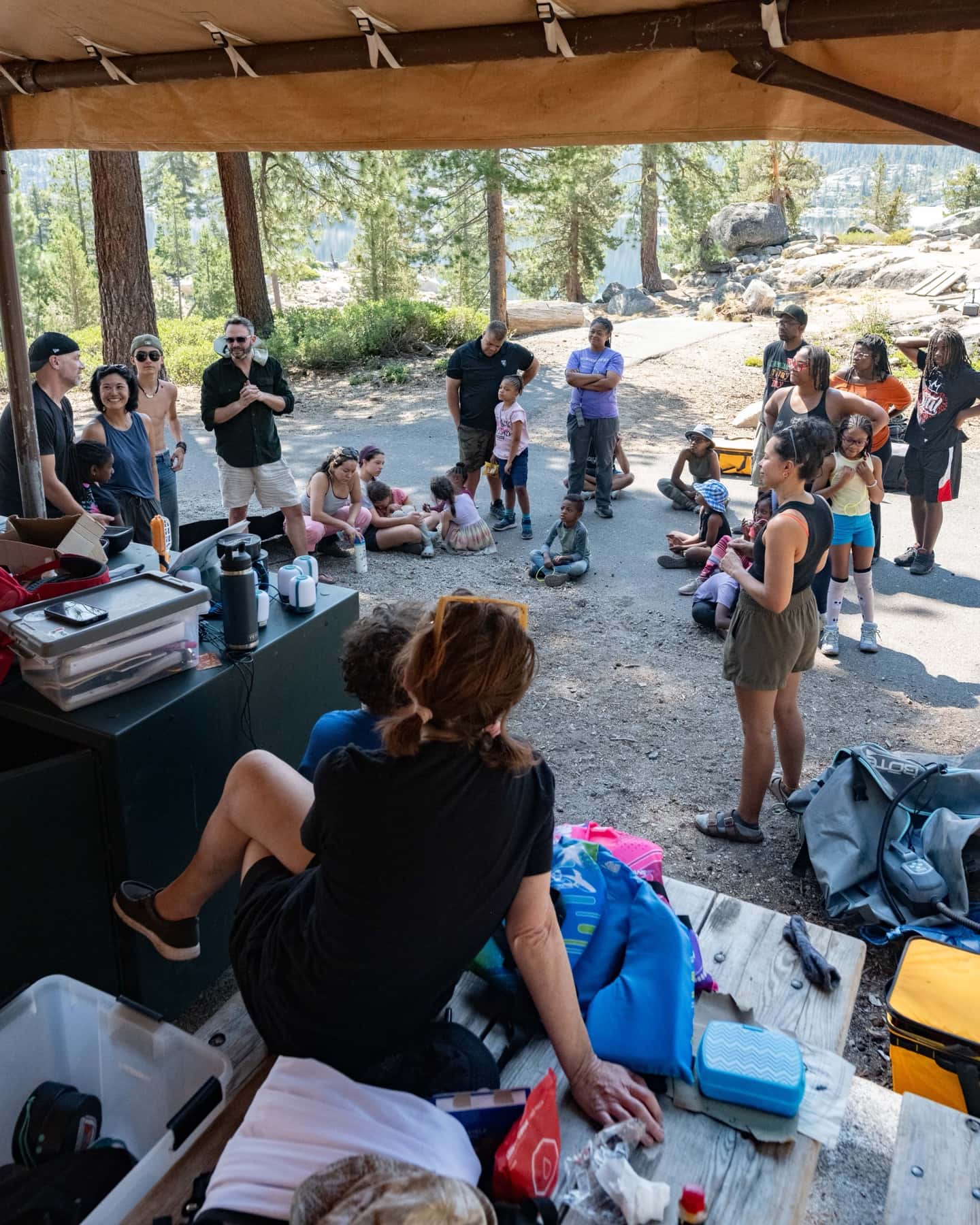 Outdoorithm families gathered under the camp kitchen canopy for a morning circle