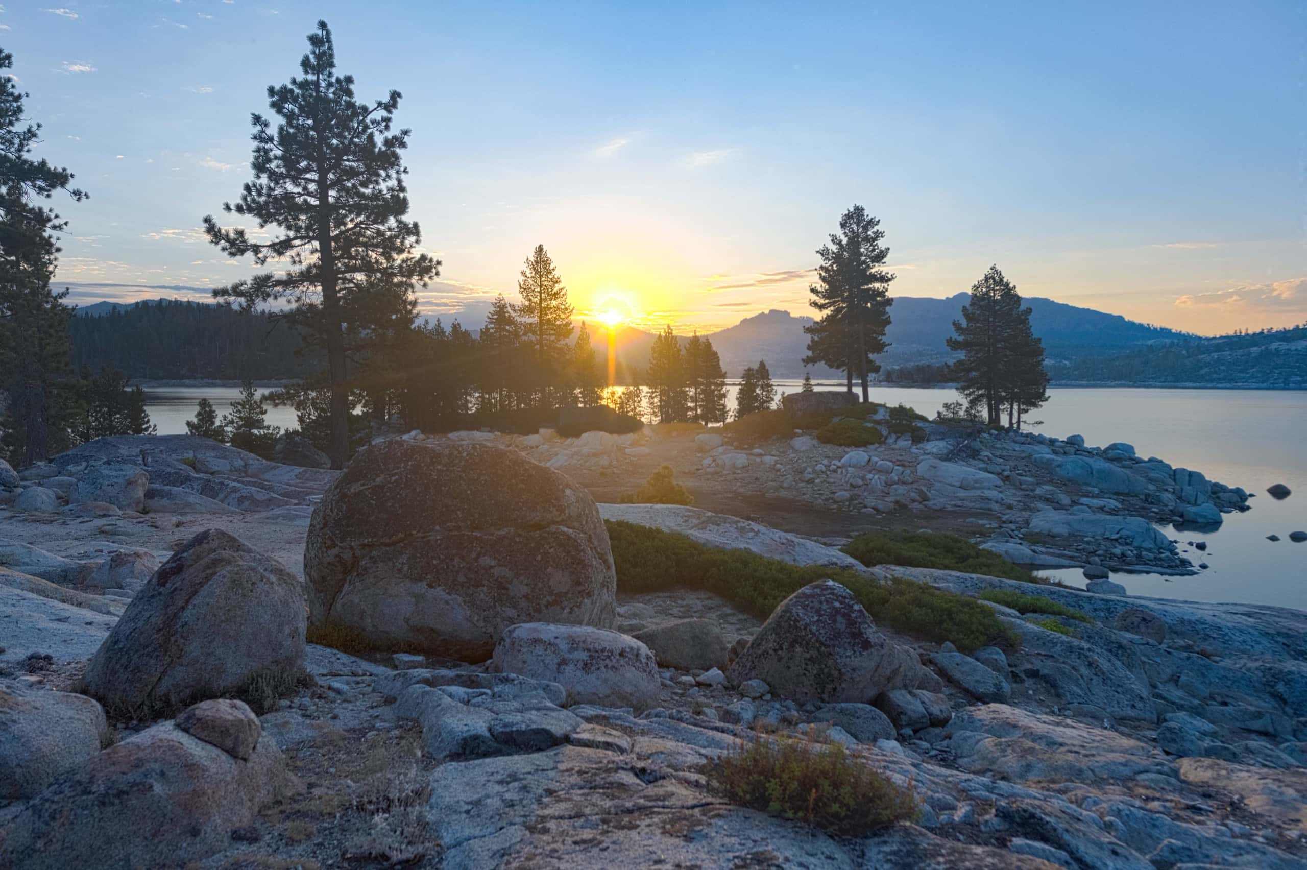 Sunset over Spicer Reservoir with glacial polished granite boulders in the foreground