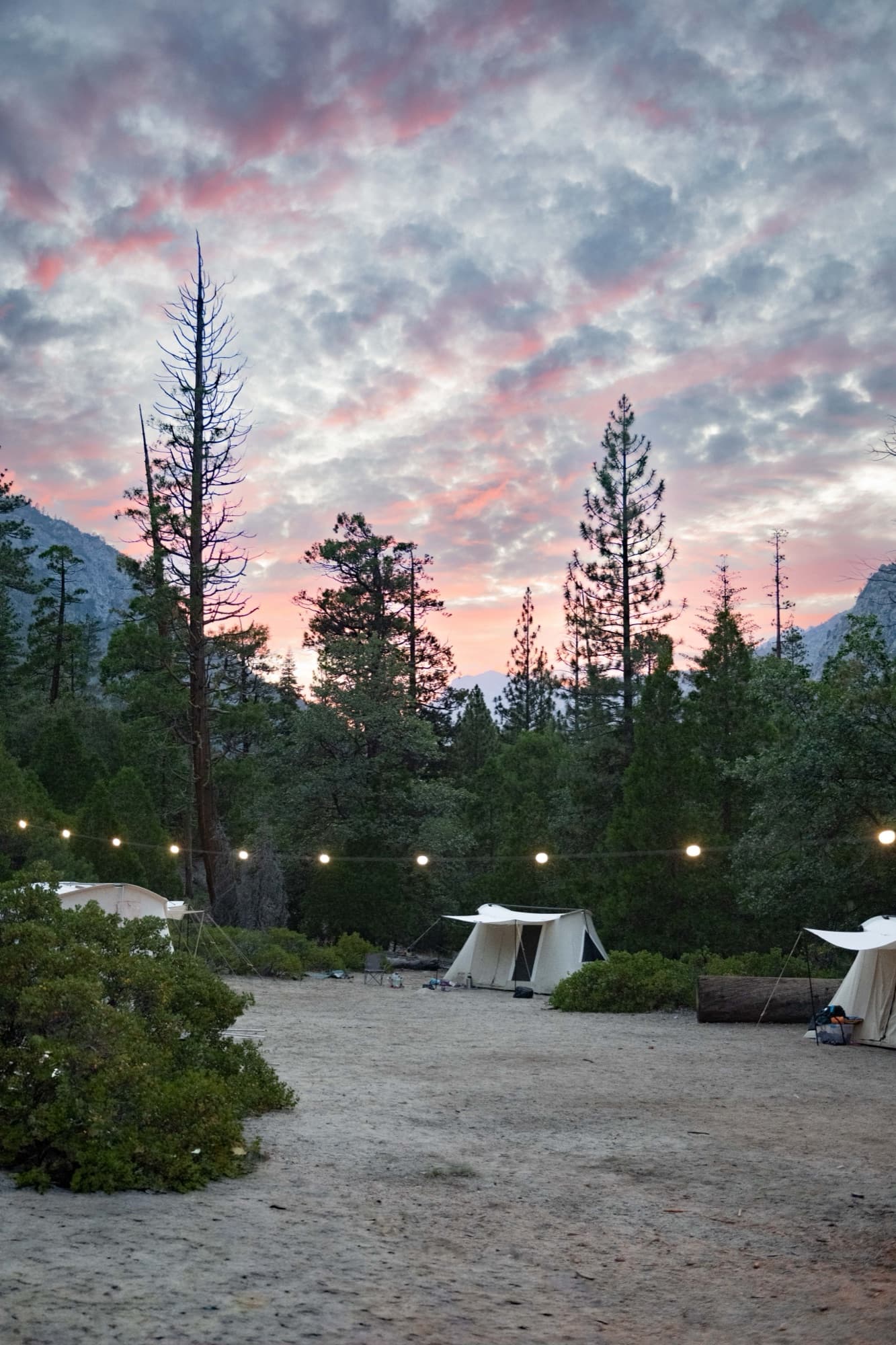 Sunset over the Outdoorithm Collective camp at Kings Canyon, canvas tents lit by string lights