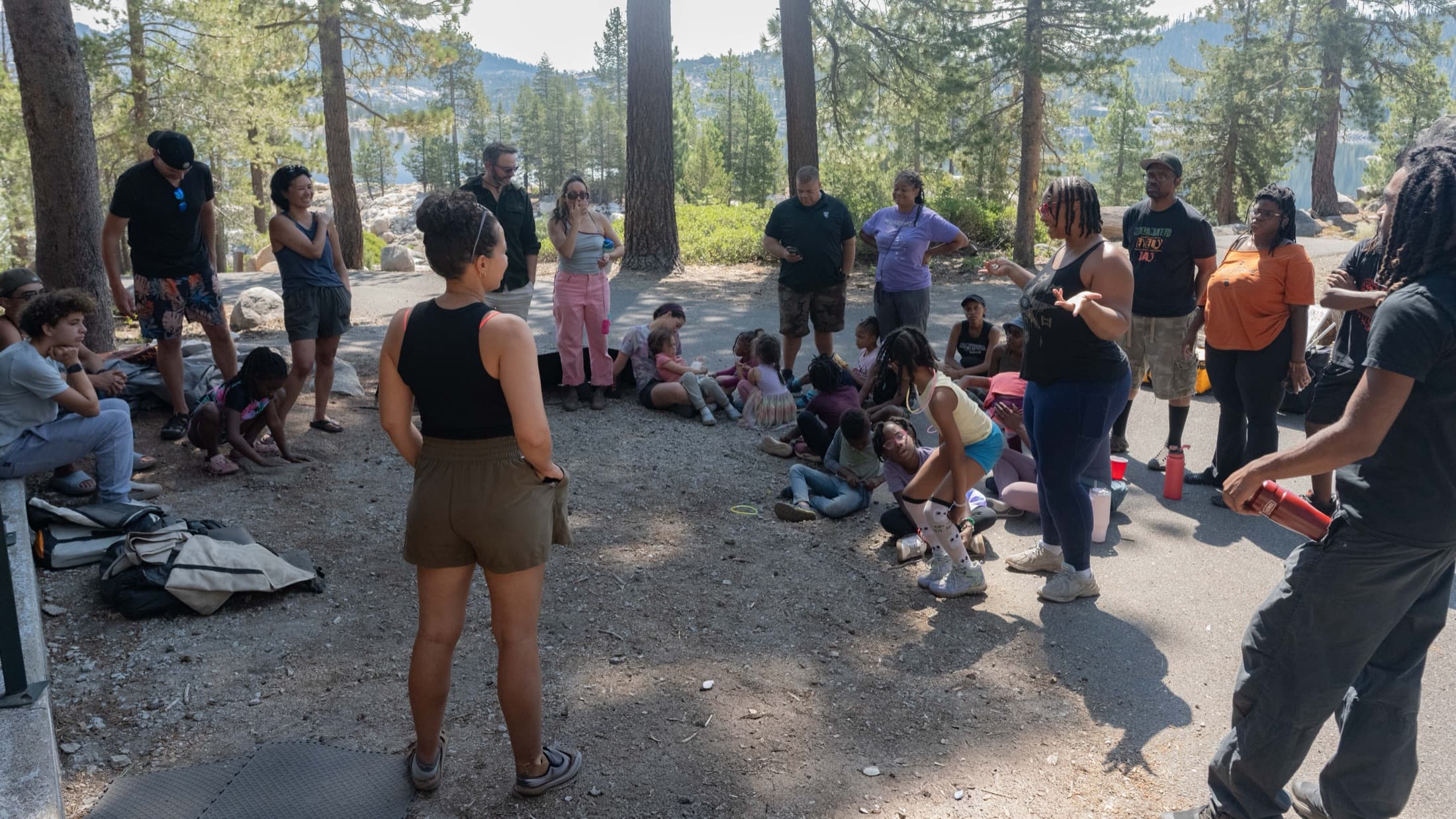 Outdoorithm Collective families seated in a circle under the pines for a morning gathering at Spicer Reservoir